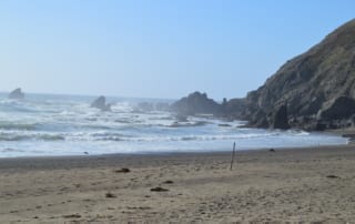 Sandy beach in California leading to large sloping hill