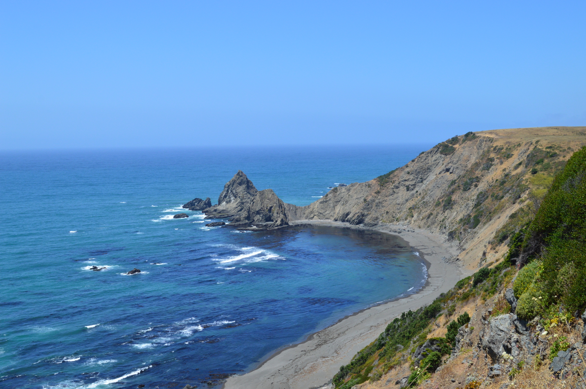Ocean off of California with large rock outcrop sticking up out of water.